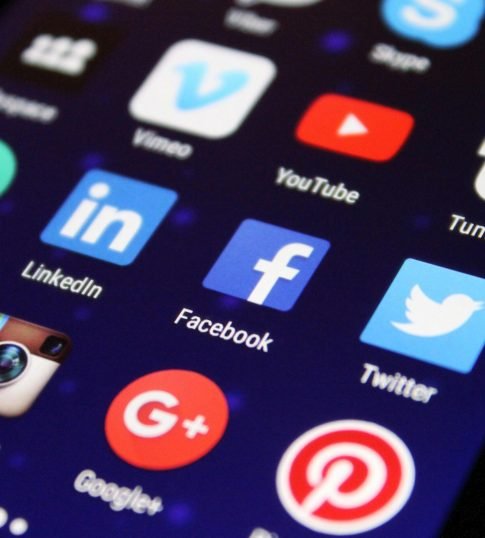 Close-up of a smartphone screen showing various social media app icons such as Facebook and Twitter.