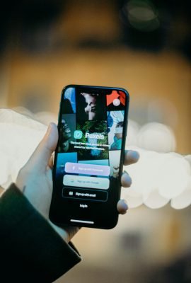 A person holding a smartphone displaying the Pexels app, highlighting the login screen.